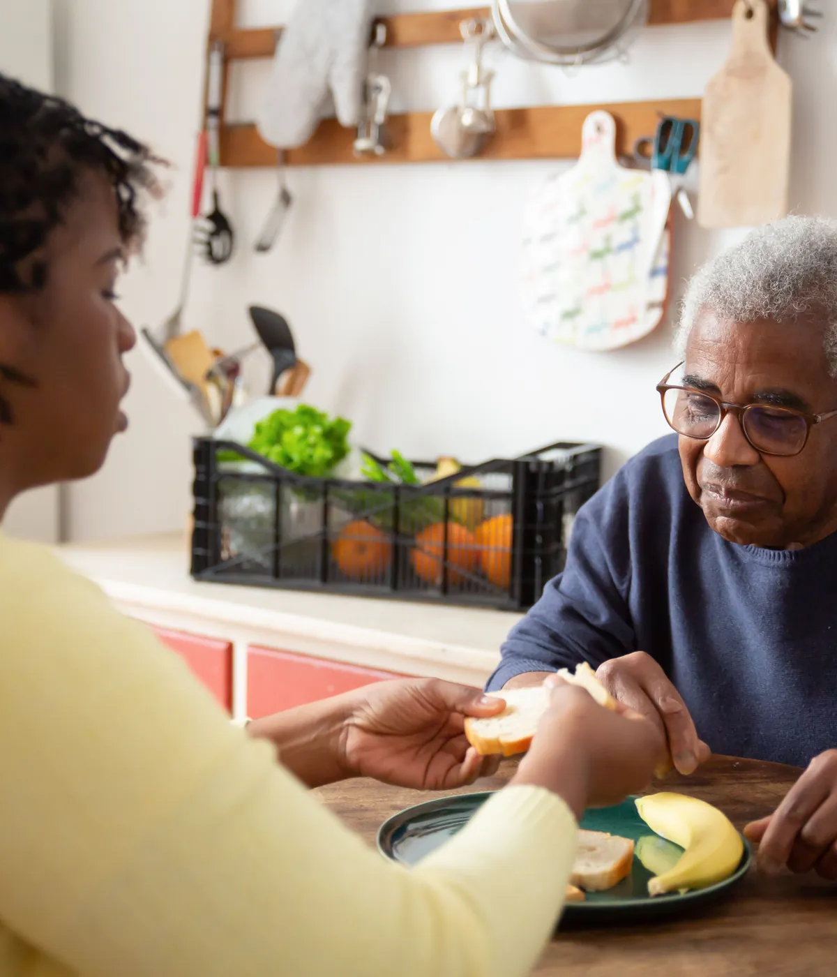 A support worker sharing a meal with an older man at his kitchen table