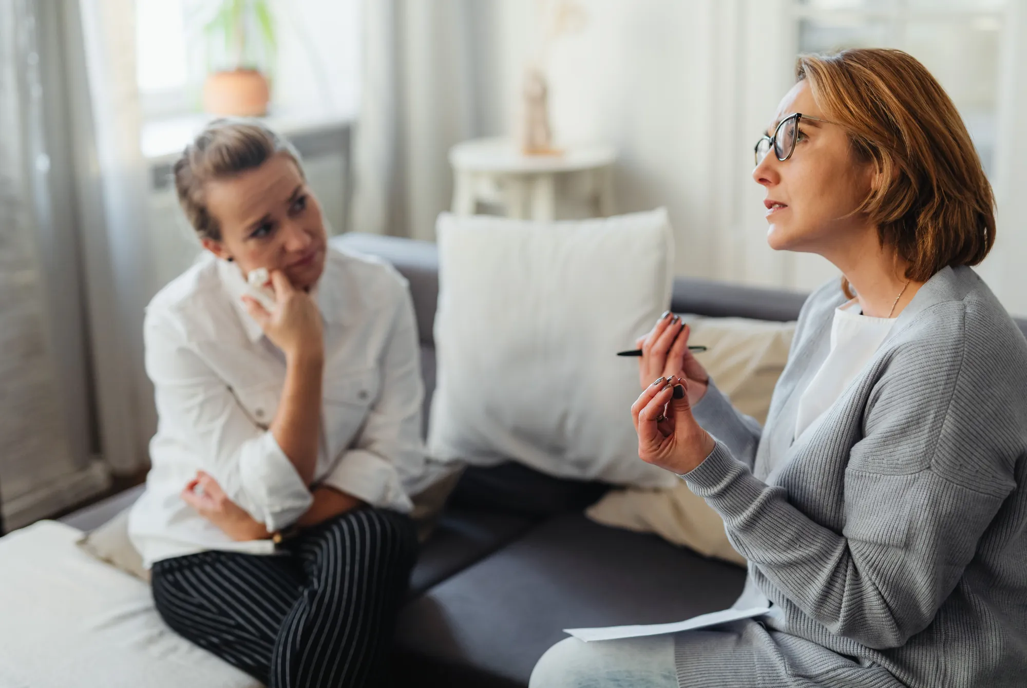 A support worker and a young woman talking things through on her sofa