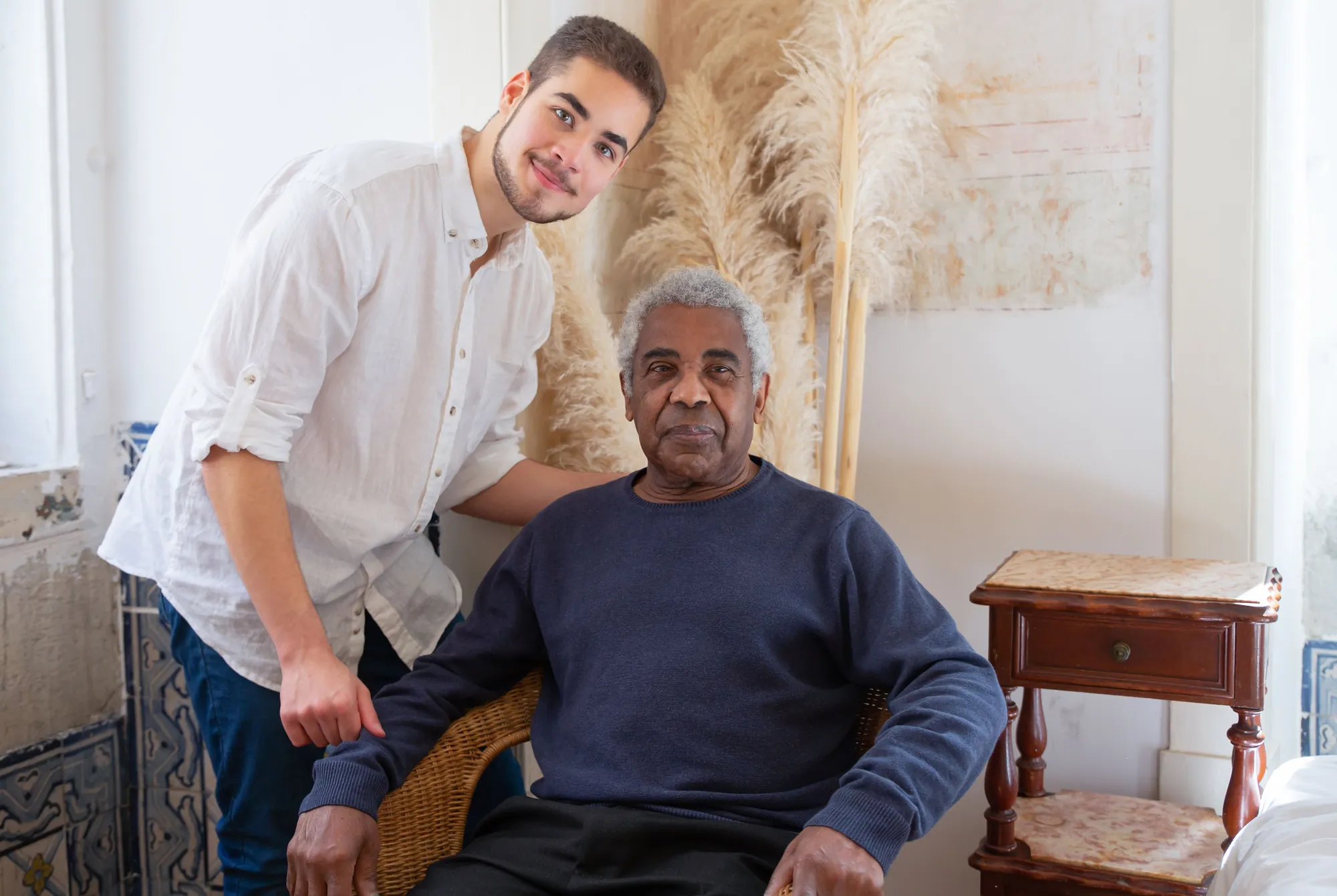 A support worker and an older man smiling together in his living room