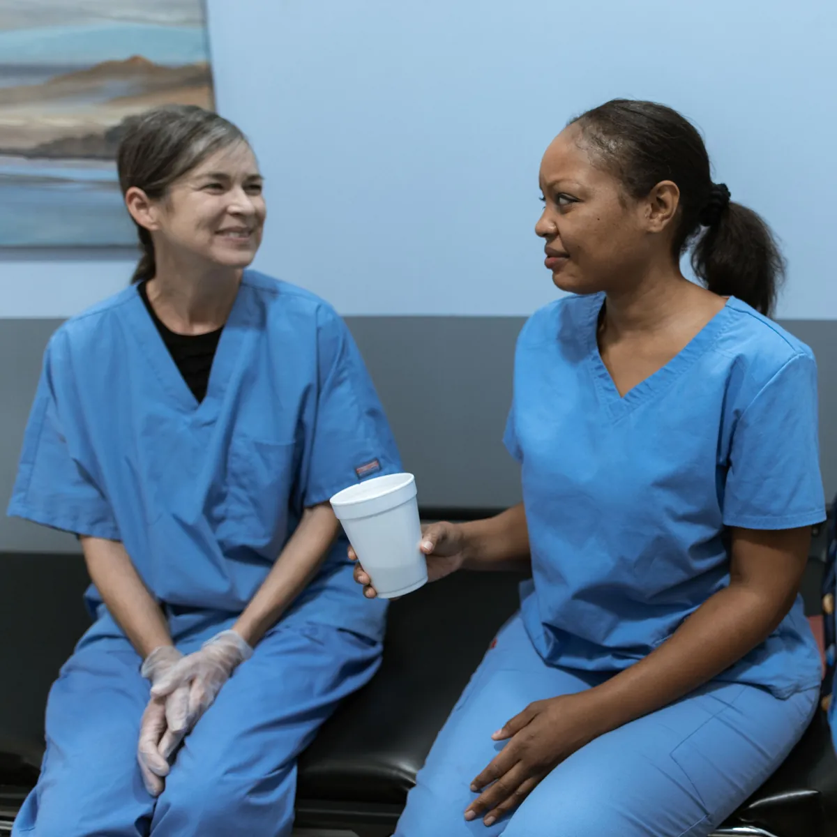 Two care workers chatting over a hot drink between visits